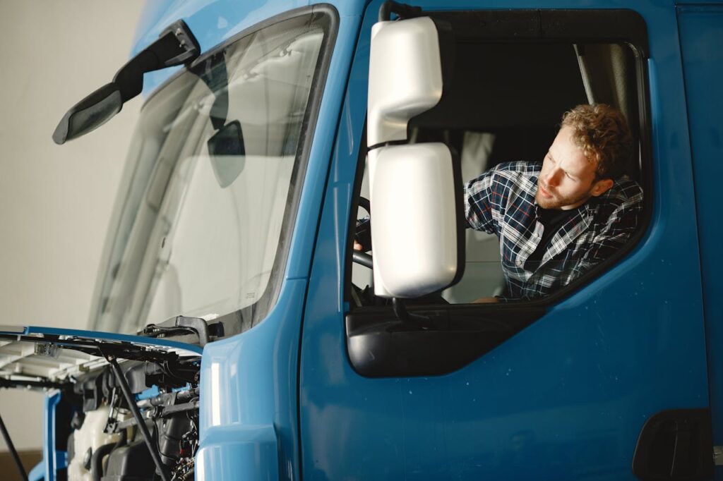 Mastering the First Impression: Your intriguing post title goes here A mechanic checks the engine of a blue truck indoors, focusing on maintenance.